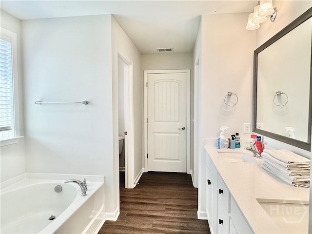 128 Melody Dr, Pooler, GA 31322 - full bathroom featuring double vanity, wood finished floors, a garden tub, toilet, and baseboards