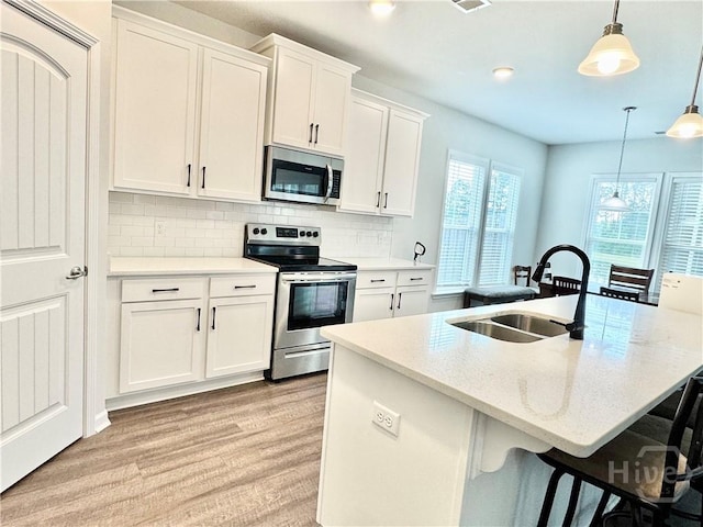 128 Melody Dr, Pooler, GA 31322 - kitchen with stainless steel appliances, a sink, light wood finished floors, backsplash, and white cabinets