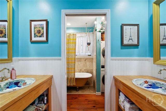 539 E Gwinnett St, Savannah, GA 31401 - full bath featuring stacked washing machine and dryer, wainscoting, a freestanding bath, wood finished floors, and curtained shower