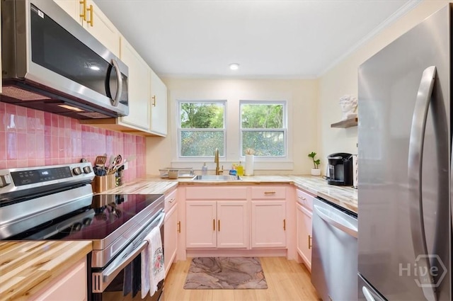 1706 E 31st St, Savannah, GA 31404 - kitchen with appliances with stainless steel finishes, a sink, light wood-style floors, backsplash, and white cabinets