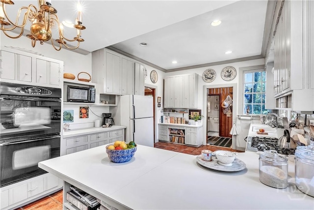 905 Goebel Ave, Savannah, GA 31404 - kitchen with black appliances, a chandelier, open shelves, a peninsula, and light countertops