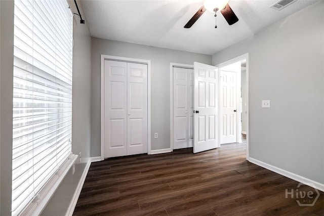 131 Warner Dr, Guyton, GA 31312 - unfurnished bedroom featuring two closets, dark wood-style floors, baseboards, and ceiling fan