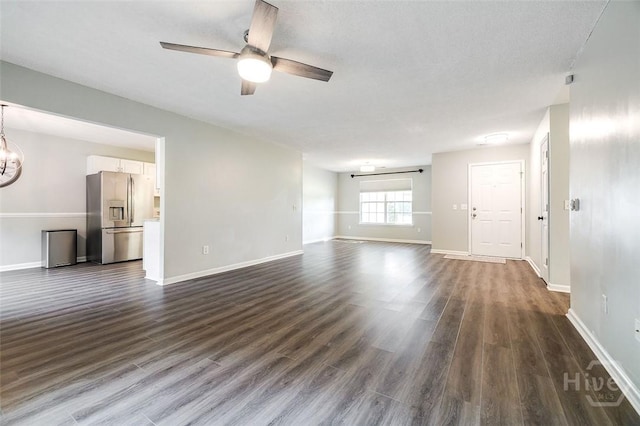 131 Warner Dr, Guyton, GA 31312 - unfurnished living room featuring ceiling fan, baseboards, dark wood-style floors, and a chandelier