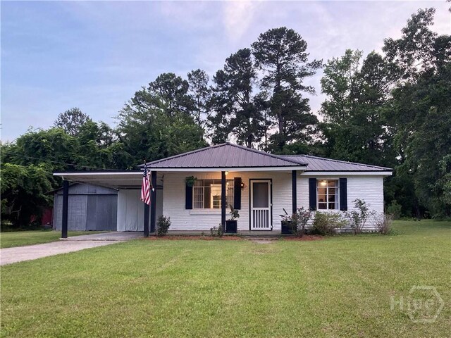 155 Oak Hill Rd, Richmond Hill, GA 31324 - ranch-style home featuring a porch, a front lawn, driveway, an attached carport, and metal roof