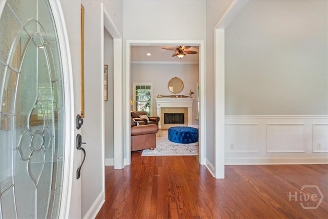 190 Sandpiper Dr, Midway, GA 31320 - entrance foyer with ceiling fan, dark wood-type flooring, a fireplace, ornamental molding, and a wainscoted wall