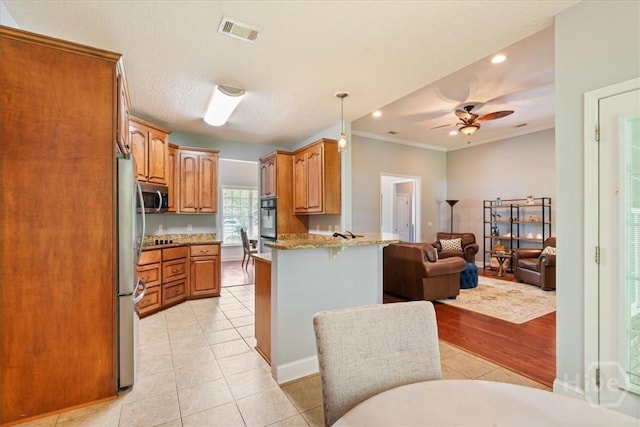 190 Sandpiper Dr, Midway, GA 31320 - kitchen featuring appliances with stainless steel finishes, a peninsula, open floor plan, brown cabinetry, and a breakfast bar area