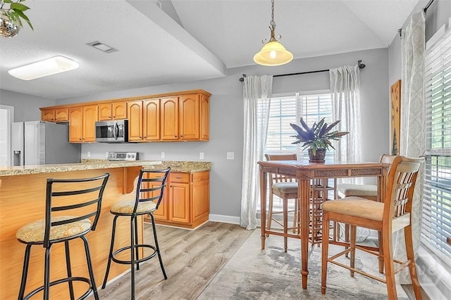207 Pink Dogwood Ln, Pooler, GA 31322 - kitchen featuring appliances with stainless steel finishes, light wood-style floors, a kitchen bar, light stone countertops, and hanging light fixtures