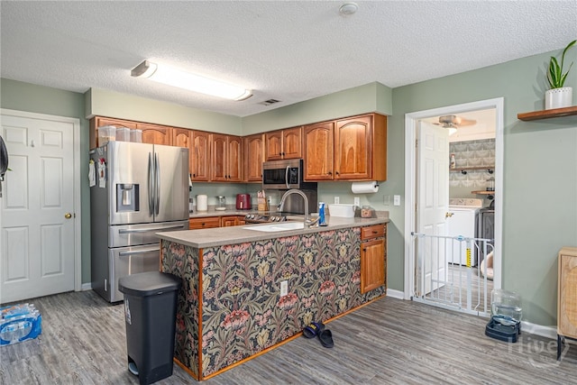 92 Shady Hill Cir, Richmond Hill, GA 31324 - kitchen featuring stainless steel appliances, washer / dryer, wood finished floors, a sink, and a textured ceiling