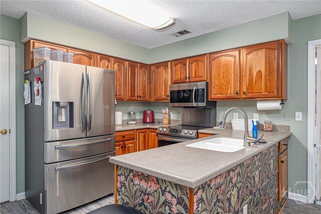92 Shady Hill Cir, Richmond Hill, GA 31324 - kitchen with appliances with stainless steel finishes, a sink, a textured ceiling, brown cabinetry, and light countertops