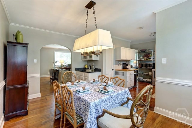 423 E 57th St, Savannah, GA 31405 - dining space with arched walkways, wood finished floors, crown molding, and baseboards