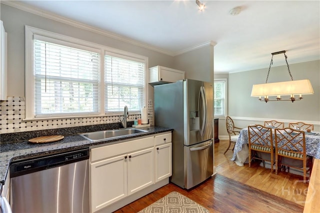 423 E 57th St, Savannah, GA 31405 - kitchen featuring stainless steel appliances, a sink, wood finished floors, ornamental molding, and white cabinetry
