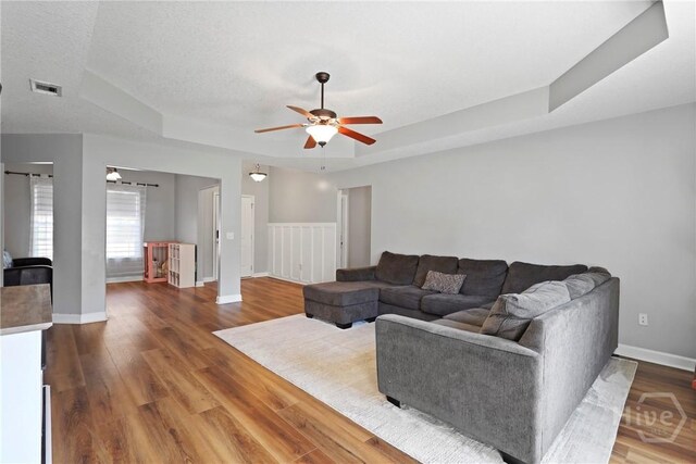 541 Deloach Rd NE, Ludowici, GA 31316 - living room with a tray ceiling, a ceiling fan, wood finished floors, baseboards, and a textured ceiling