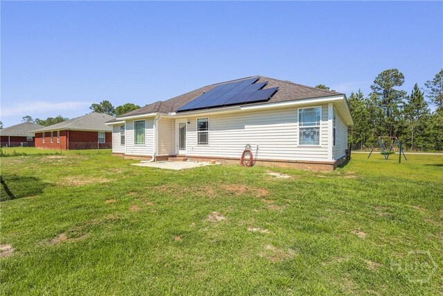 541 Deloach Rd NE, Ludowici, GA 31316 - rear view of property with solar panels, a patio, a yard, and a playground