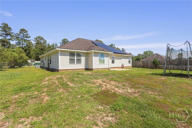 541 Deloach Rd NE, Ludowici, GA 31316 - back of house with a trampoline, roof mounted solar panels, and central AC