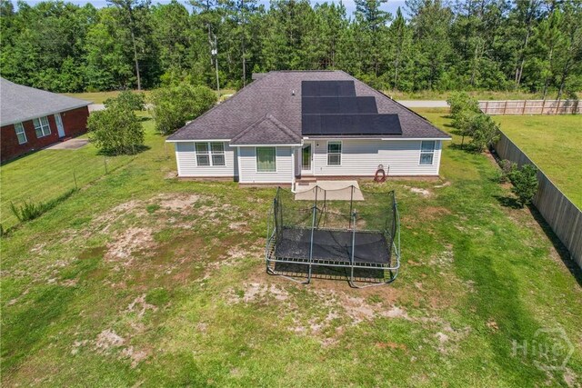 541 Deloach Rd NE, Ludowici, GA 31316 - rear view of property with solar panels, a trampoline, a wooded view, and a shingled roof