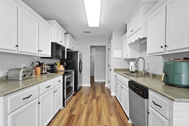 541 Deloach Rd NE, Ludowici, GA 31316 - kitchen with stainless steel appliances, a sink, white cabinetry, and light wood finished floors