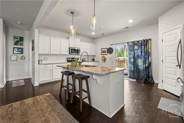 40 Saddlebrush Rd, Ellabell, GA 31308 - kitchen with stainless steel appliances, light stone countertops, dark wood-style floors, white cabinets, and decorative backsplash