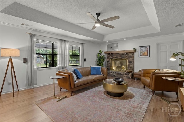 107 Rose Dhu Way, Savannah, GA 31419 - living room with a textured ceiling, a ceiling fan, light wood-style flooring, a raised ceiling, and a fireplace