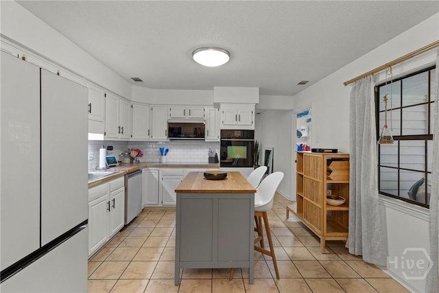 107 Rose Dhu Way, Savannah, GA 31419 - kitchen with appliances with stainless steel finishes, decorative backsplash, white cabinetry, and light tile patterned flooring