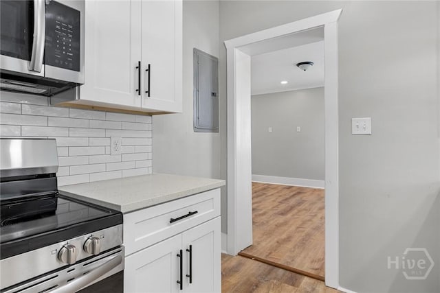 1825 Lloyd St, Savannah, GA 31405 - kitchen featuring stainless steel appliances, decorative backsplash, light wood-style floors, light stone counters, and electric panel