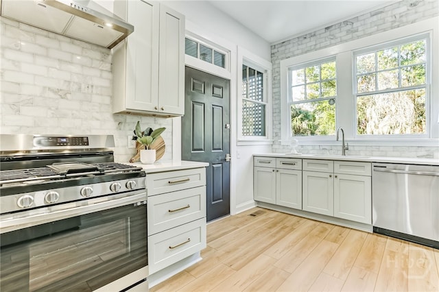 1001 Maupas Ave, Savannah, GA 31401 - kitchen with appliances with stainless steel finishes, a sink, backsplash, light countertops, and light wood-type flooring