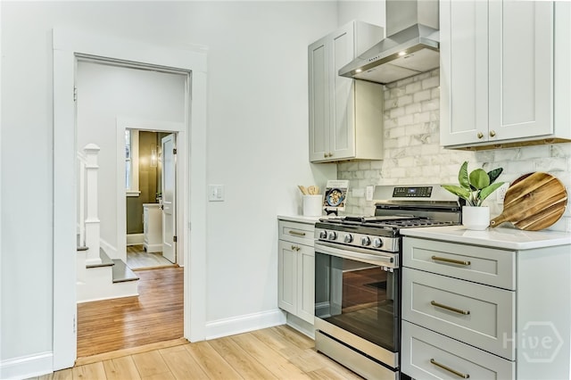 1001 Maupas Ave, Savannah, GA 31401 - kitchen with gas stove, wall chimney exhaust hood, light wood-style floors, backsplash, and light countertops