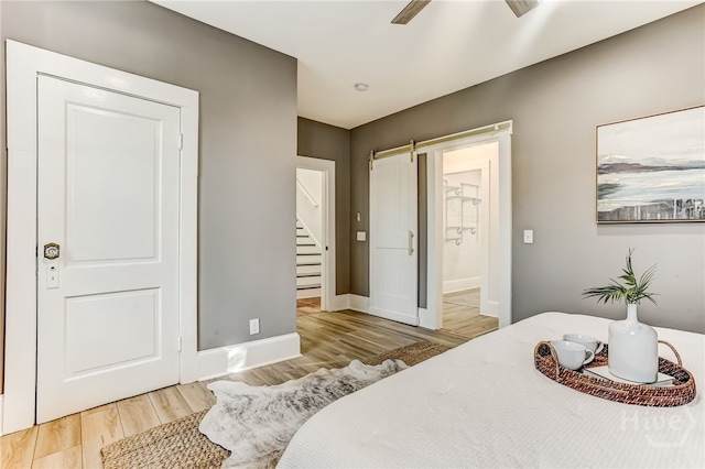 1001 Maupas Ave, Savannah, GA 31401 - bedroom featuring a barn door, wood finished floors, baseboards, connected bathroom, and ceiling fan