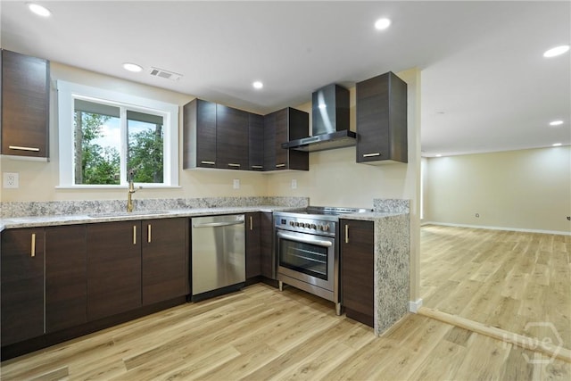 40 Circle Dr, Pembroke, GA 31321 - kitchen featuring appliances with stainless steel finishes, wall chimney exhaust hood, light wood-type flooring, dark brown cabinetry, and recessed lighting