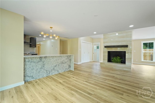 40 Circle Dr, Pembroke, GA 31321 - unfurnished living room featuring a tiled fireplace, light wood-style flooring, recessed lighting, and a chandelier