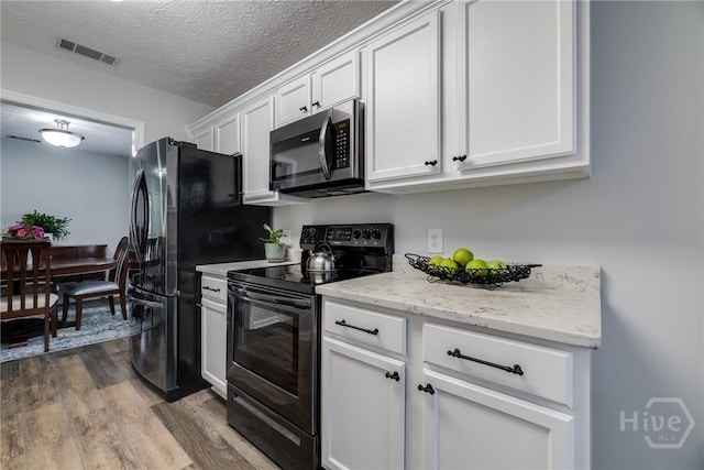 19 S Lake Dr, Savannah, GA 31410 - kitchen with black range with electric stovetop, dark wood-style flooring, white cabinetry, light stone counters, and a textured ceiling