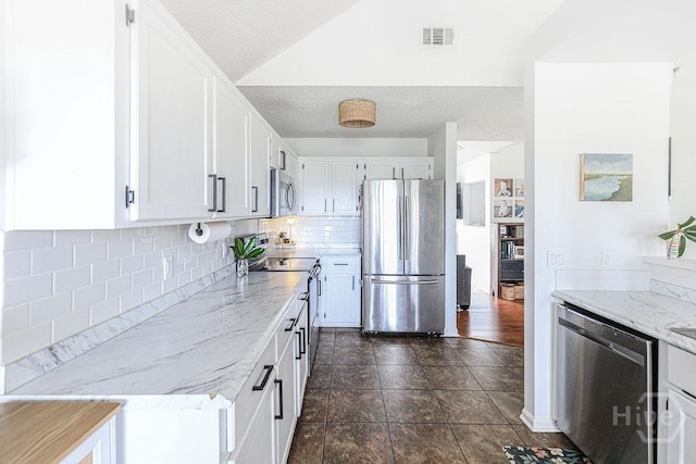 111 Runner Rd, Savannah, GA 31410 - kitchen featuring appliances with stainless steel finishes, white cabinetry, tasteful backsplash, light stone counters, and vaulted ceiling