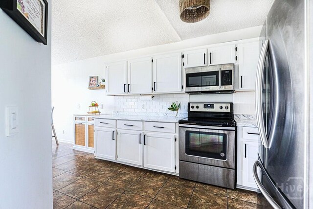 111 Runner Rd, Savannah, GA 31410 - kitchen with appliances with stainless steel finishes, tasteful backsplash, a textured ceiling, white cabinets, and vaulted ceiling