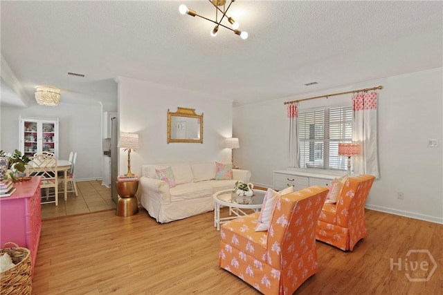 5109 Laroche Ave, Savannah, GA 31404 - living room featuring a chandelier, light wood-type flooring, a textured ceiling, and baseboards
