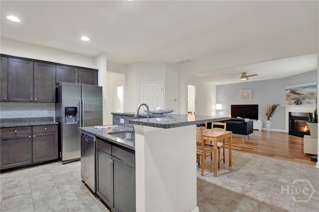 106 Tanzania Trl, Pooler, GA 31322 - kitchen featuring appliances with stainless steel finishes, dark stone countertops, a kitchen island with sink, a sink, and open floor plan