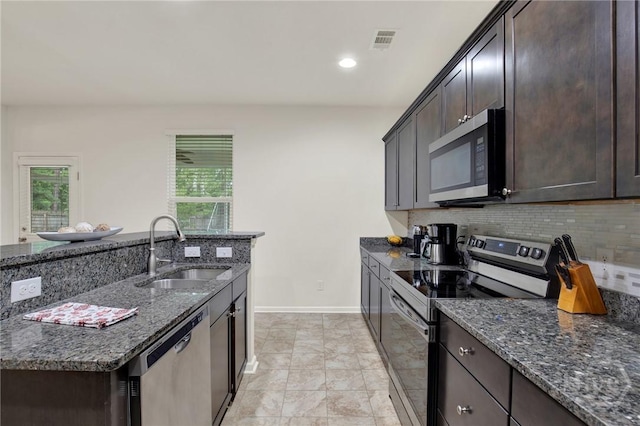 106 Tanzania Trl, Pooler, GA 31322 - kitchen featuring stainless steel appliances, a sink, dark stone counters, decorative backsplash, and dark brown cabinets