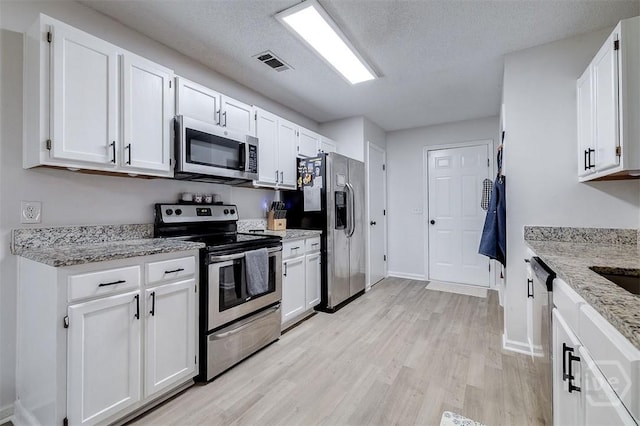 5 Sugar Cane Dr, Savannah, GA 31419 - kitchen with appliances with stainless steel finishes, light wood-style flooring, white cabinets, light stone countertops, and a textured ceiling