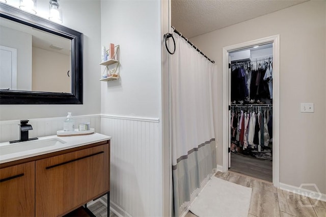 5 Sugar Cane Dr, Savannah, GA 31419 - bathroom with vanity, wainscoting, a spacious closet, a shower with curtain, and a textured ceiling