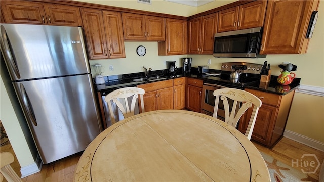 18 Silver Ave Unit 4, Tybee Island, GA 31328 - kitchen featuring appliances with stainless steel finishes, a sink, light wood finished floors, brown cabinets, and baseboards