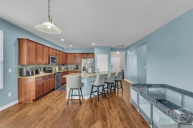 413 Lions Den Dr, Pooler, GA 31322 - kitchen featuring appliances with stainless steel finishes, wood finished floors, tasteful backsplash, brown cabinetry, and recessed lighting