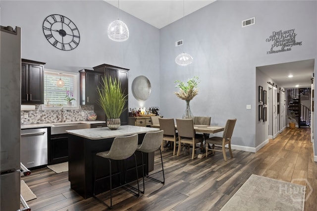 4000 Old River Rd S, Brooklet, GA 30415 - kitchen with a high ceiling, stainless steel dishwasher, a sink, dark wood-style flooring, and a breakfast bar area