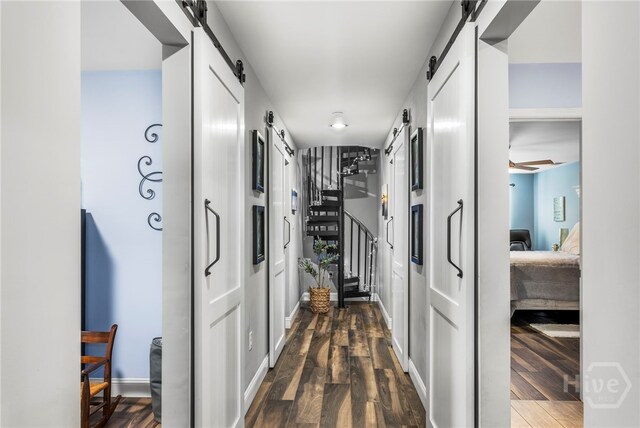 4000 Old River Rd S, Brooklet, GA 30415 - corridor featuring a barn door, dark wood-style flooring, stairs, and baseboards