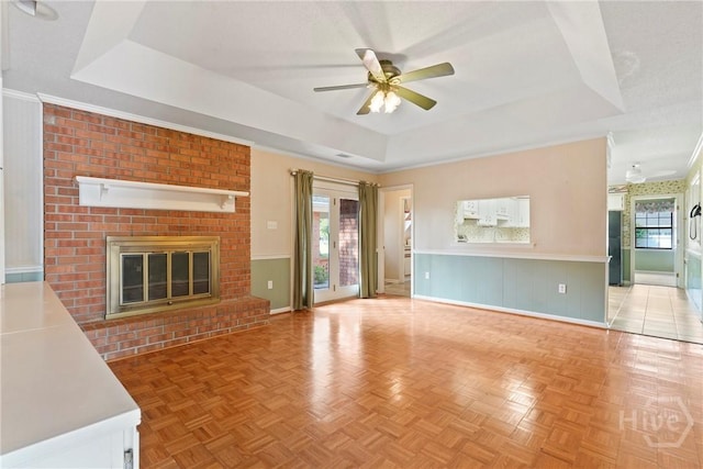145 Cardinal Rd, Savannah, GA 31406 - unfurnished living room featuring a raised ceiling, ceiling fan, a fireplace, wainscoting, and baseboards