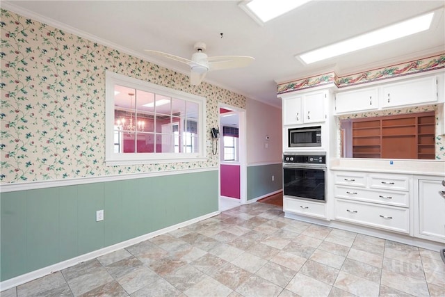 145 Cardinal Rd, Savannah, GA 31406 - kitchen with oven, stainless steel microwave, white cabinets, a wainscoted wall, and wallpapered walls