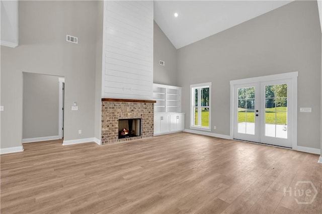 1362 Ebenezer Rd, Rincon, GA 31326 - unfurnished living room featuring high vaulted ceiling, french doors, baseboards, light wood-style floors, and a fireplace