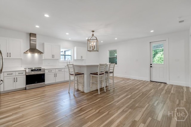238-A W Magnolia Ave, Savannah, GA 31419 - kitchen featuring wall chimney range hood, stainless steel electric range, light wood-style floors, a breakfast bar area, and a sink