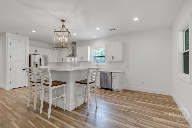 238-A W Magnolia Ave, Savannah, GA 31419 - kitchen with appliances with stainless steel finishes, a kitchen bar, wall chimney exhaust hood, light wood-type flooring, and white cabinets