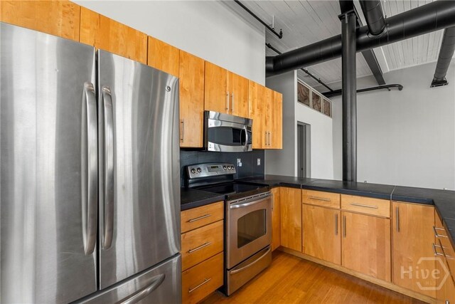 301 W Broughton St Unit 3B, Savannah, GA 31401 - kitchen with appliances with stainless steel finishes, light wood finished floors, brown cabinets, and dark countertops