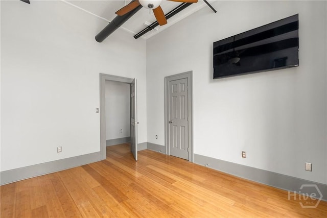301 W Broughton St Unit 3B, Savannah, GA 31401 - unfurnished bedroom featuring wood finished floors, baseboards, a ceiling fan, and a towering ceiling
