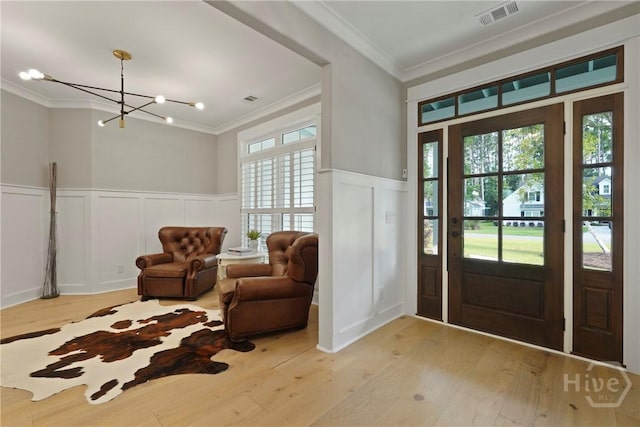 315 Linkside Lake Dr, Richmond Hill, GA 31324 - foyer entrance featuring a decorative wall, crown molding, a chandelier, light wood-style flooring, and wainscoting