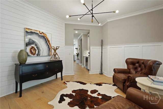 315 Linkside Lake Dr, Richmond Hill, GA 31324 - living area featuring crown molding, a chandelier, light wood-type flooring, a wainscoted wall, and a decorative wall